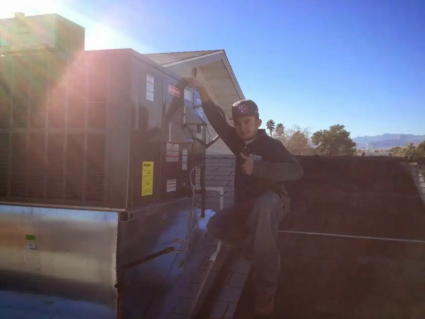HVAC technician performing Heat Pump Repair on a rooftop unit in Jan Phyl Village
